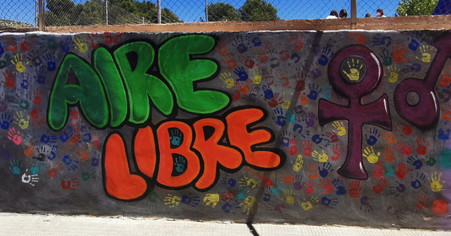 Mural de Aire Libre pintado por el alumnado con las huellas de sus manos en el patio del colegio