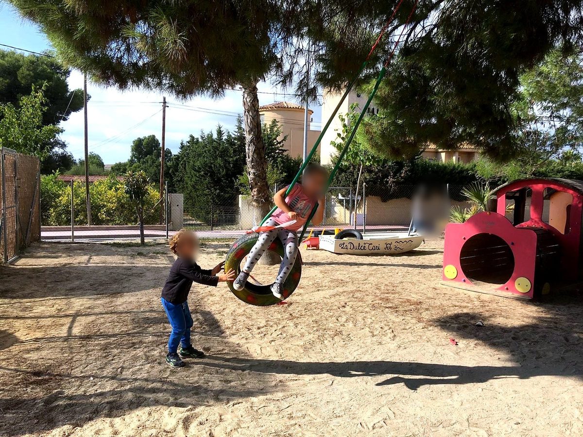 Niña y niño de Infantil jugando en el columpio del patio del Colegio Aire Libre, en Alicante