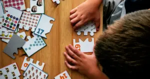 Niño encajando por sí mismo las piezas de un puzle de números sobre una mesa de madera