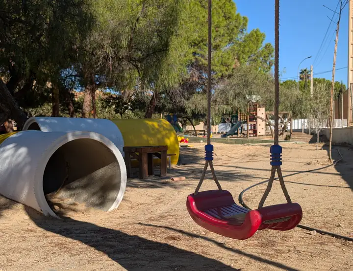 Columpios y túnel del patio de Infantil entre árboles